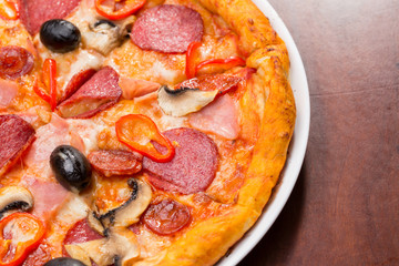 Italian pizza with salami, cheese, mushrooms and olives on a wooden table