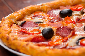 Italian pizza with salami, cheese, mushrooms and olives on a wooden table