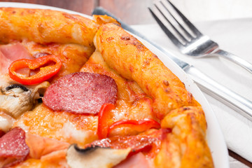 Italian pizza with salami, cheese, mushrooms and olives on a wooden table