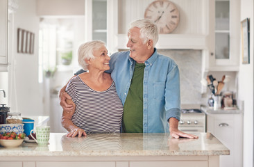 Content seniors standing in each other's arms together at home
