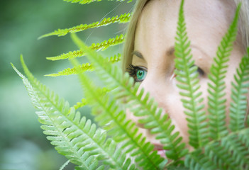 Abstract portrait.Beautiful young woman with green  eyes hidden behind fern leaves