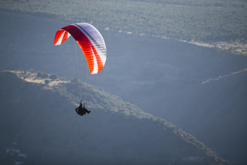 Paraglider flying over mountains.