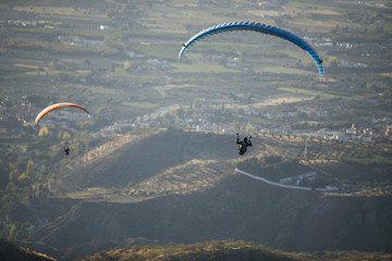 Paraglider flying over mountains.