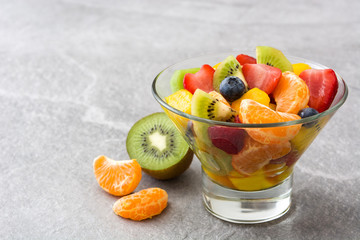 Fruit salad in crystal bowl on gray stone
