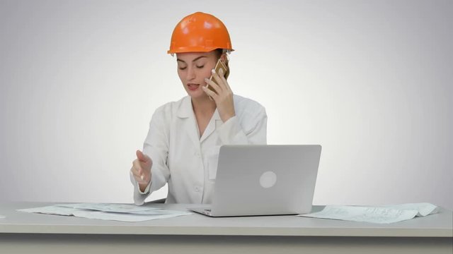 Woman in orange hardhat calling the phone discussing constraction plan on white background.