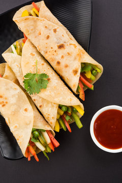 Indian popular snack food called Vegetable spring rolls or veg franky made using vegetables wrapped inside paratha/chapati/roti with tomato ketchup.