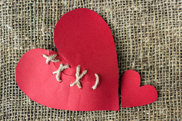 A broken red heart. Sewn thread. The concept of divorce, separation.