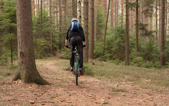 Young man riding a mountain bike through the woods.