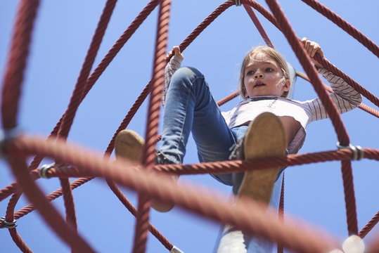 Active young child girl climbing the spider web playground activity. Children summer activities. - Powered by Adobe