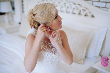 Fototapeta na wymiar Close up portrait of pretty bride in hotel room. Woman in white dress. Luxury wedding day.