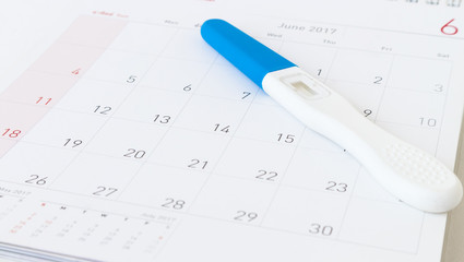 Pregnancy test on calendar background, health care concept