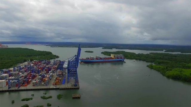 Aerial footage of a tugboat pushing the container ship to the port