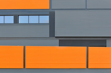 Architectural background. Wall of the modern orange and black corrugated metal panels.