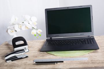 Laptop auf Holztisch mit Blume,Locher,Tacker