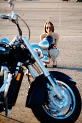 Foto op Plexiglas Attractive woman biker squatting behind her motorcycle. © Iryna