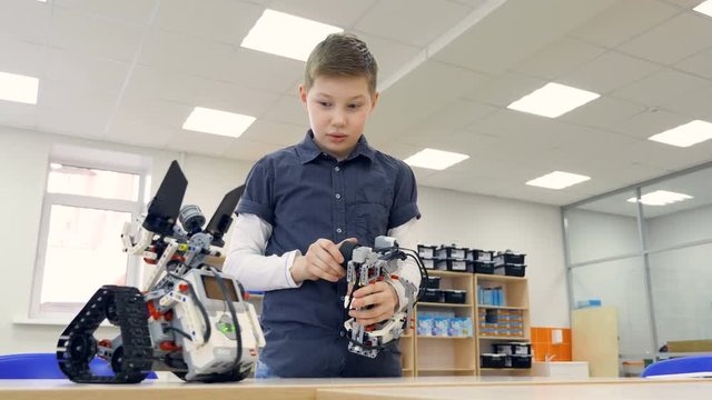 Student boy testing robot in robotechnics school classroom. Engineer education concept. 4K.