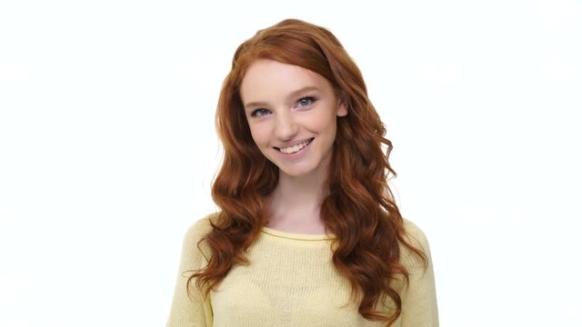 Smiling happy girl with long red ginger hair showing peace gesture isolated over white 