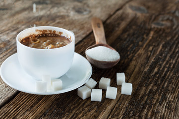 cup of coffee with milk and sugar spoon on the table