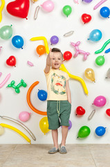 Fototapeta premium boy on a white background with colorful balloons. boy in a tank top and shorts on a white background with balloons in the shape of a heart