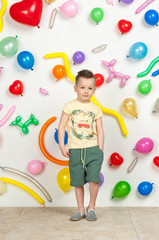 Fototapeta premium boy on a white background with colorful balloons. boy in a tank top and shorts on a white background with balloons in the shape of a heart