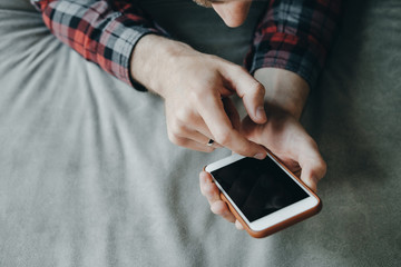 Man hands in red checkered shirt using a touch screen smart phone hands close up