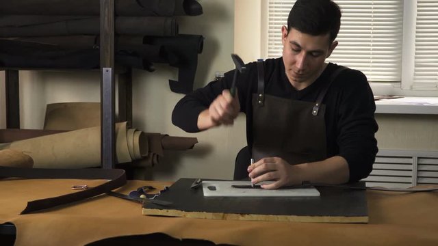 Craftsman working with a piece of leather on the table. Making a leather product. 

