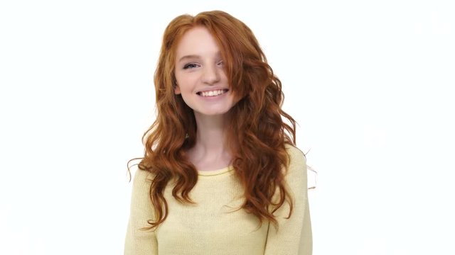 Happy pretty smiling girl playing with her red curly hair isolated over white