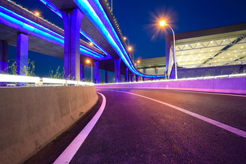 Fototapeta premium Empty road floor with city viaduct bridge of neon lights night