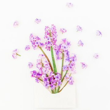 Bouquet of pink hyacinth flowers, petals and envelope on white background. Flat lay, top view.