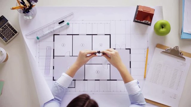 woman with blueprint, ruler and dividers at office