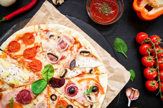 Italian pizza with ingredients and vegetables, spices on black background. Flat lay, top view.