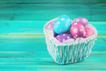 Blue Basket in the form of heart with Easter eggs. Blue wooden background. Happy easter.