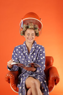 Eine Frau sitzt lachend unter Trockenhaube