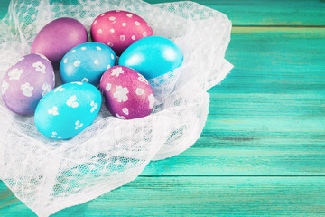 Violet and blue Easter eggs on white fabric. Blue wooden background. Happy easter.