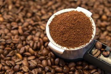 Professional metal holder with freshly ground coffee on coffee beans background