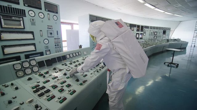  Astronaut alone in mission control room, pressing switches on control panel
