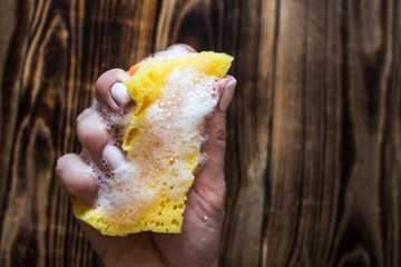sponge with soap bubbles in woman's hand