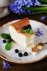 Vertical close-up of homemade cottage cheese casserole with blackberry and mint on a plate. Selective focus. 