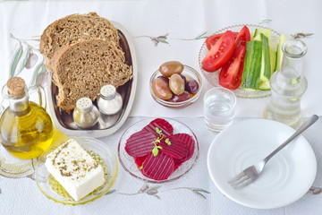 Greek food, mezedes. Jars with olive oil and vine vinegar, olives,feta, tzatziki, dark bread, raki, beetroot, fresh cucumber and tomato on a white background. Healthy eating concept. Healthy food.