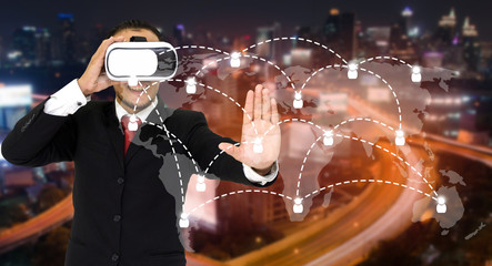 Young asian businessman wearing VR virtual reality headset, business and technology concept for future with world map social media connection on blurred night city background, color tone effect.