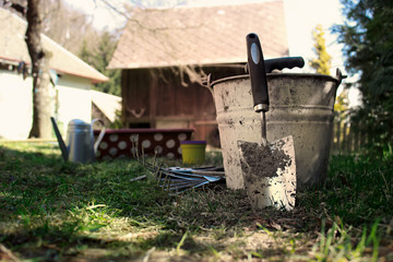 Fototapeta na wymiar Gardening Tools on House Yard with Wooden Barn in Background