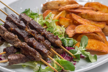 Lamb skewers on salad with wedges potatoes