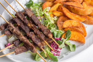 Lamb skewers on salad with wedges potatoes