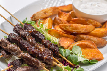 Lamb skewers on salad with wedges potatoes