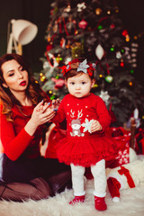Attaractie young mother poses with her little girl before green Christmas tree