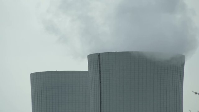 Close up time-lapse shot on a cloudy and overcast day of the top of two cooling towers used by an electricity generating station.