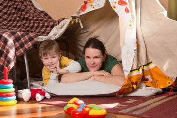 Mother and  little son playing children room with play tent.  Happy loving family.  .