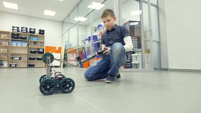 Young boy engineer testing self-made robot at engineering lab. 4K.
