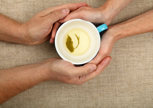 Man and woman hands hold empty green tea cup