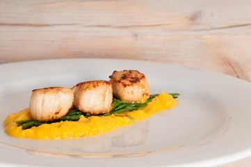 gourmet seafood dish of scallops and asparagus on a white plate